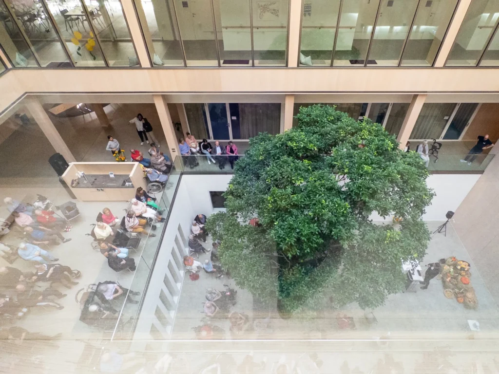 Festlich geschmückter Innenhof im Pflegezentrum Baar mit grossem Baum, Bewohnerinnen, Bewohnern und Gästen beim Erntedankfest.