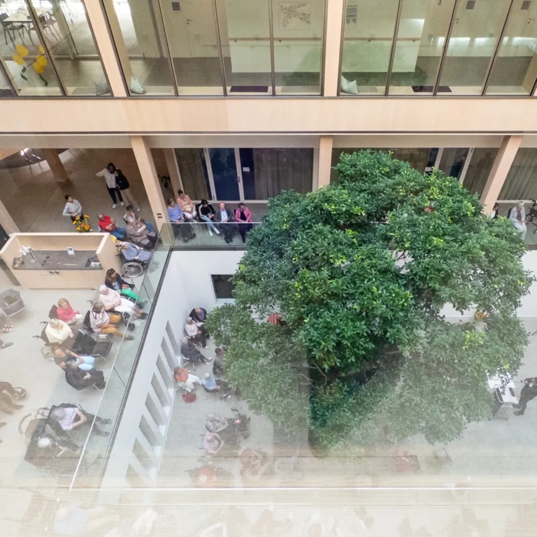 Festlich geschmückter Innenhof im Pflegezentrum Baar mit grossem Baum, Bewohnerinnen, Bewohnern und Gästen beim Erntedankfest.